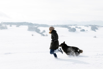 Germany, Baden-Wuerttemberg, Waldshut-Tiengen, woman and dog running in snow
