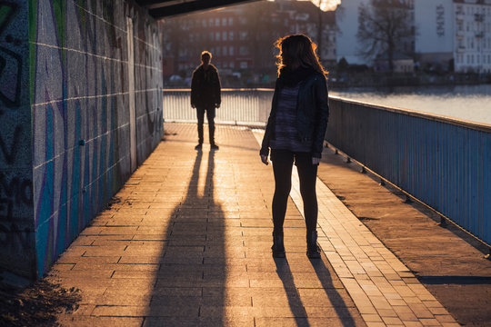 Germany, Berlin, teenage couple standing under a bridge at evening sunlight