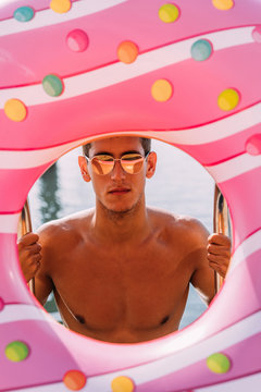 Portrait of young man behind inflatable float in donut shape