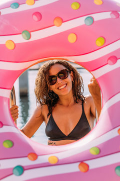 Portrait of happy young woman behind inflatable float in donut shape
