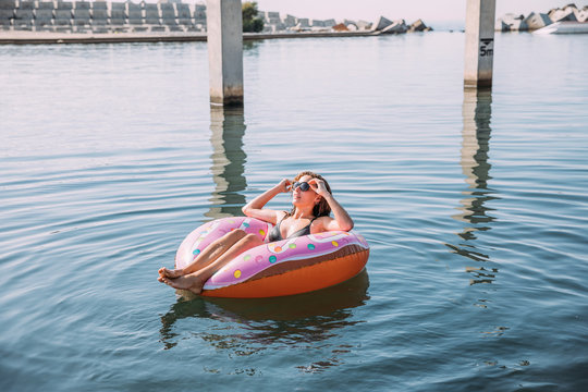 Young woman bathing in the sea on inflatable float in donut shape
