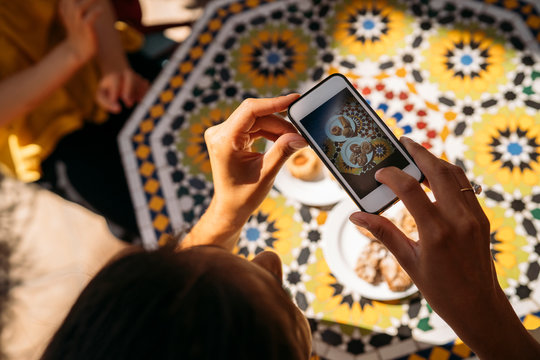 Close-up of woman taking a picture of cakes in a Moroccan cafe