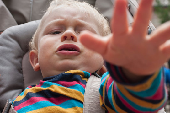 Portrait of unhappy toddler sitting in buggy