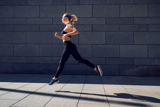 Woman in black sportswear training jumping outdoors in a sun light ray