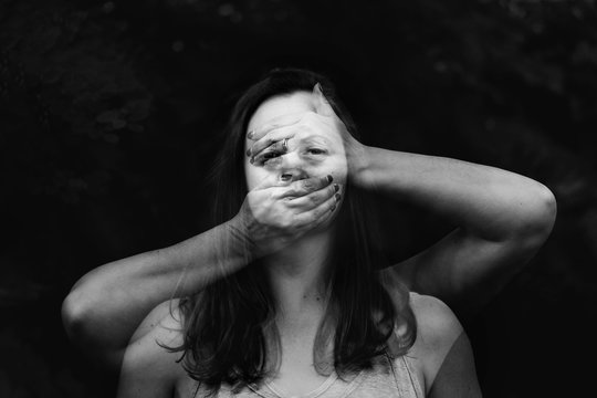 Black and white double exposure portrait of woman behind hands
