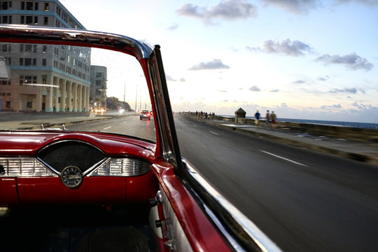The Malecon in Havana in Cuba from a classic convertible red car - Powered by Adobe