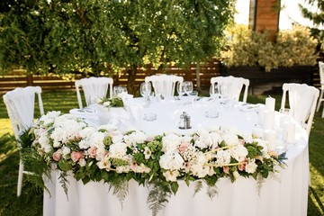 White wedding table setting at outdoor reception.