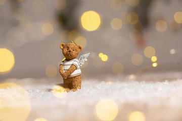 Decorative figurines of a Christmas theme. Figurine of a cute bear with angel wings. Festive decor, warm bokeh lights