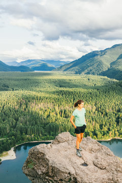 Hiker looking at green hills and lake from the edge in Washington