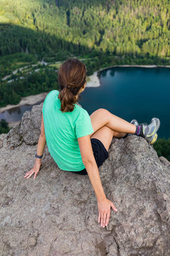 Hiker looking at green hills and lake from the edge in Washington