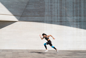Pulled back view of female athlete running on concrete vertical