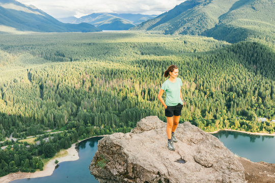 Hiker looking at green hills and lake from the edge in Washington