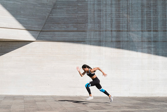 Pulled Back View Of Female Athlete Running On Concrete Vertical