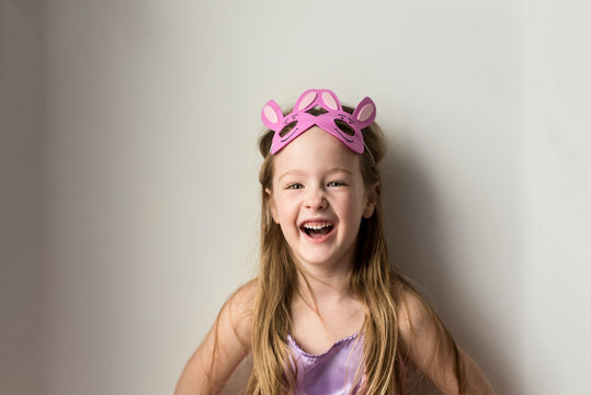 Laughing girl with bunny rabbit headband against while wall