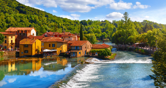 Borghetto Valeggio sul Mincio, Verona, Italy. Italian traditional village with vintage colorful houses above river. Stone bridge among ancient architecture. Flowers and greens. Summer sunny day.