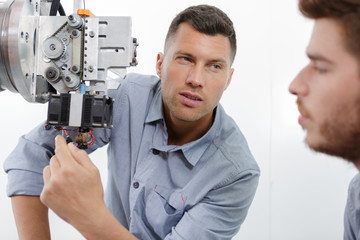 Naklejka na ściany i meble ophthalmologist examining young man with optometric machine