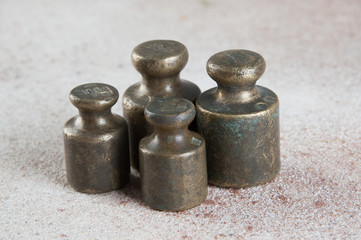 Antique bronze weights for scales on concrete background.