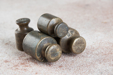 Antique bronze weights for scales on concrete background.