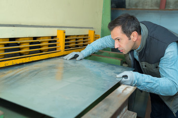 worker bends a metal plate on the industrial machine