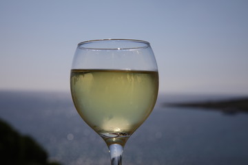 Cold white wine in a glass on a warm evening.A beautiful wine glass,water droplets on misted glass.Aperitif in Bodrum Turkey restaurant, in front of the Aegean sea at sunset. Copy space for your text