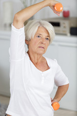 pleasant senior woman lifting up dumbbells