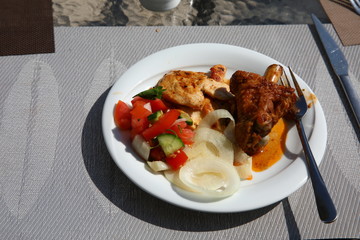 Turkey stew in soy sauce and white chicken meat with fresh vegetables on one large white plate close-up.Salad of tomatoes cucumbers and onion rings to poultry meat for lunch.Hearty food