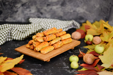 Delicious homemade cookies with apples and walnuts. Sweet pastries with an autumn theme and autumn yellow leaves. Autumn appetizing background.