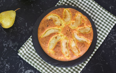 Homemade pear pie on a black table with pears in the background.