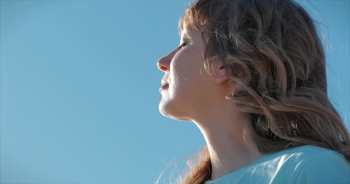 Portrait of a European woman or girl raising her face to the sun. A woman receives vitamin D from the sun