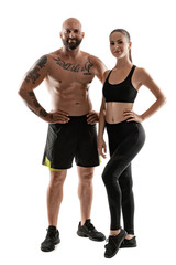 Fototapeta na wymiar Athletic man in black shorts and sneakers with brunette woman in leggings and top posing isolated on white background. Fitness couple, gym concept.