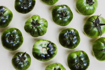 Green tomatoes of different shapes on a white background close-up. Conceptually for cooking and gardening.
