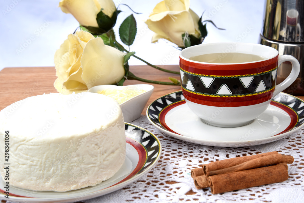 Wall mural cup of tea with cheese on wooden table, brazilian breakfast