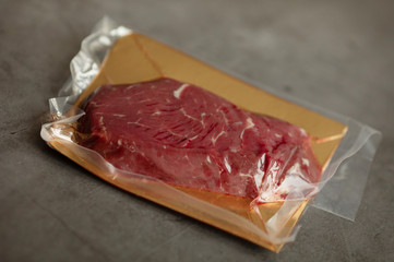 Raw meat vacuum-packed,  steaks on a wooden board.