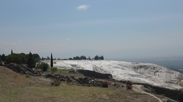 Pamukkale, Denizli, Turkey - 16th of July 2019: 4K Parachute soars in sky above Pamukkale sinter terraces 