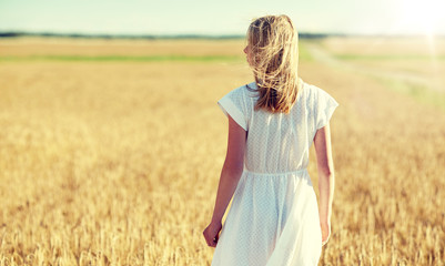 Fototapeta na wymiar happiness, nature, summer holidays, vacation and people concept - young woman in white dress on cereal field