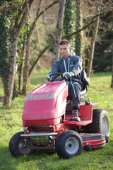 gardener driving a riding lawn mower in garden