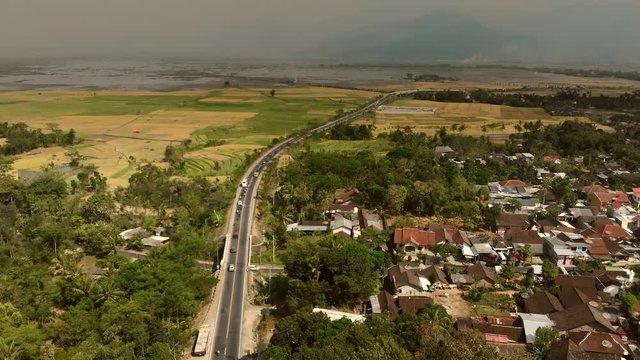 Aerial footage bird view of bypass highway road in Ambarawa city, Central Java, Indonesia with foggy volcano background