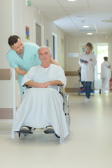 nurse pushing an elderly mans wheelchair