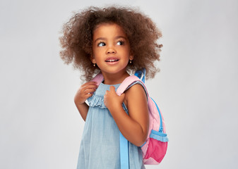 childhood, school and education concept - happy little african american girl with backpack over grey background