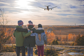 Children  standing on the mountain and watches how the plane lands. Children outdoors. Sunset. Travel.