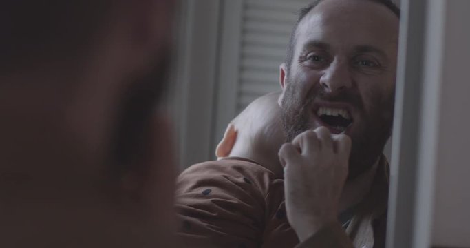Single father brushing teeth in bathroom, holding baby