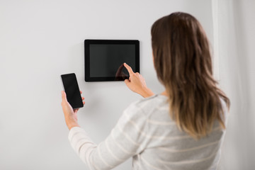 automation, internet of things and technology concept - woman using tablet pc computer and smartphone at smart home