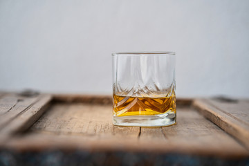 Shimmering glass of whisky on rustic shabby wooden table in front of white background