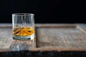 Golden shimmering whisky in a beautiful glass on a rustic wooden shabby table