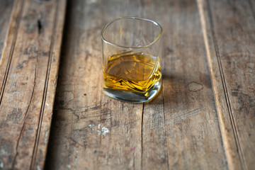 Close up of beautiful glass with golden whisky on an old rustic wooden table