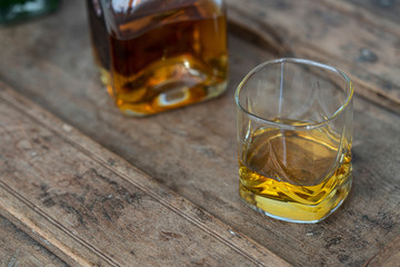 Bourbon in glass and bottle on a rustic wooden shabby table