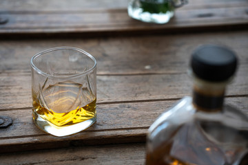 Glass of whisky and bottle on a wooden rustic barrel