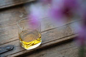 Glass of scotch whisky on rustic wooden barrel with reflections