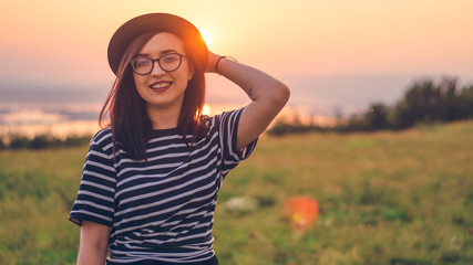 Closeup of a beautiful young woman with a sunset behind her