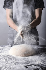 Posypywanie ciasta bochenka chleba mąką osoba w fartuchu piekarz - obrazy, fototapety, plakaty